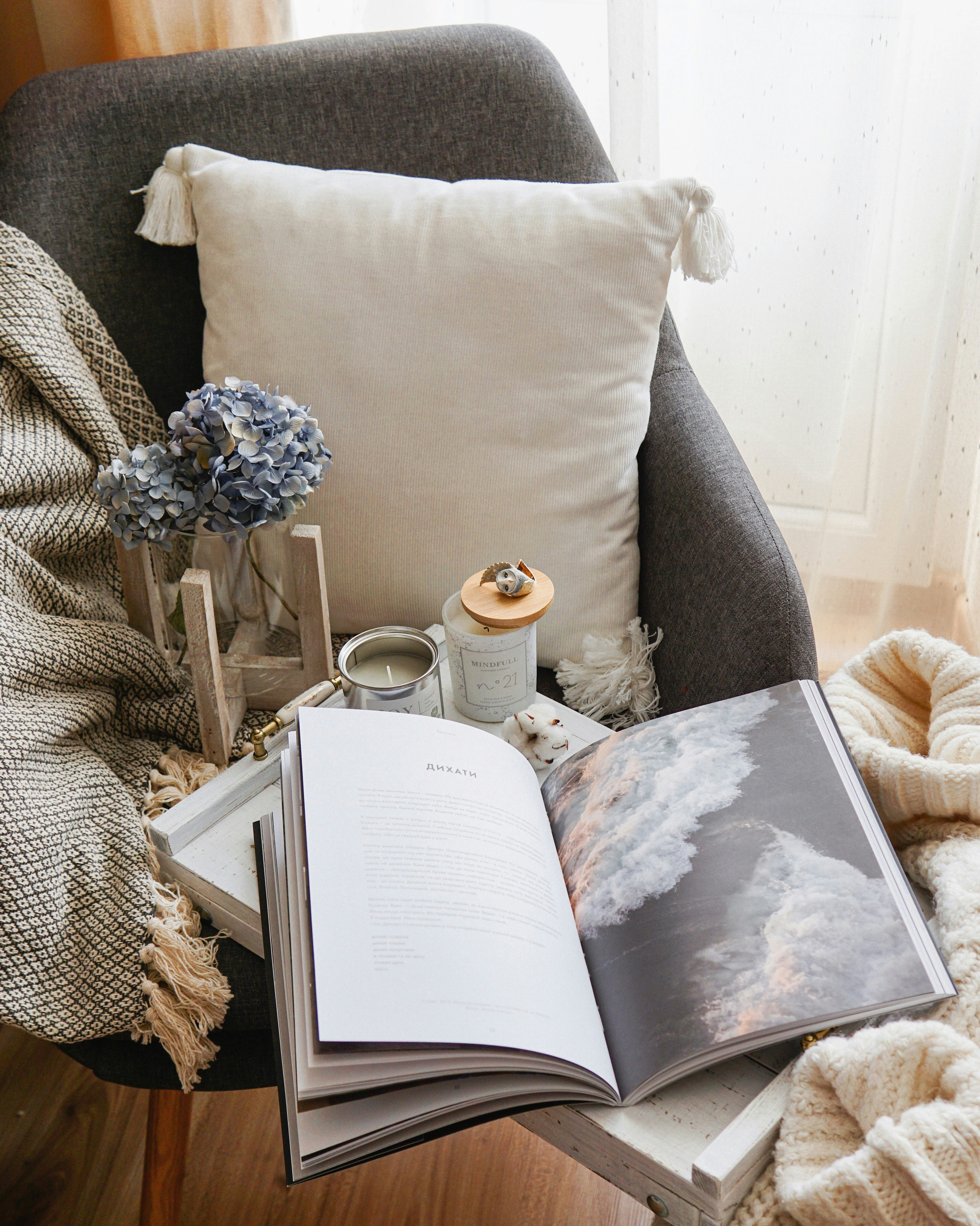 A quiet reading corner with an open book, candles and soft blankets